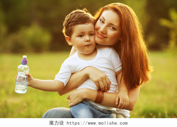 母亲抱着拿着一瓶水的儿子